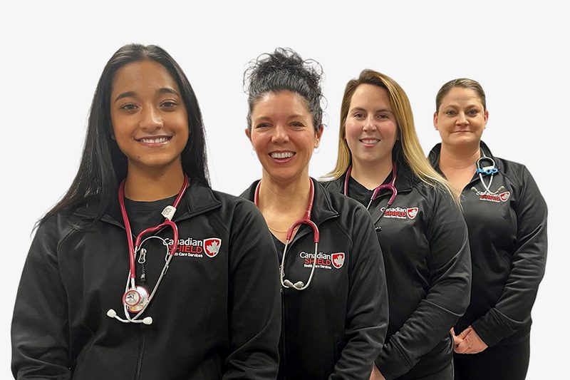 Four female staffs from Canadian Shield Health standing back to back wearing their uniform along with stethoscopes around their necks.